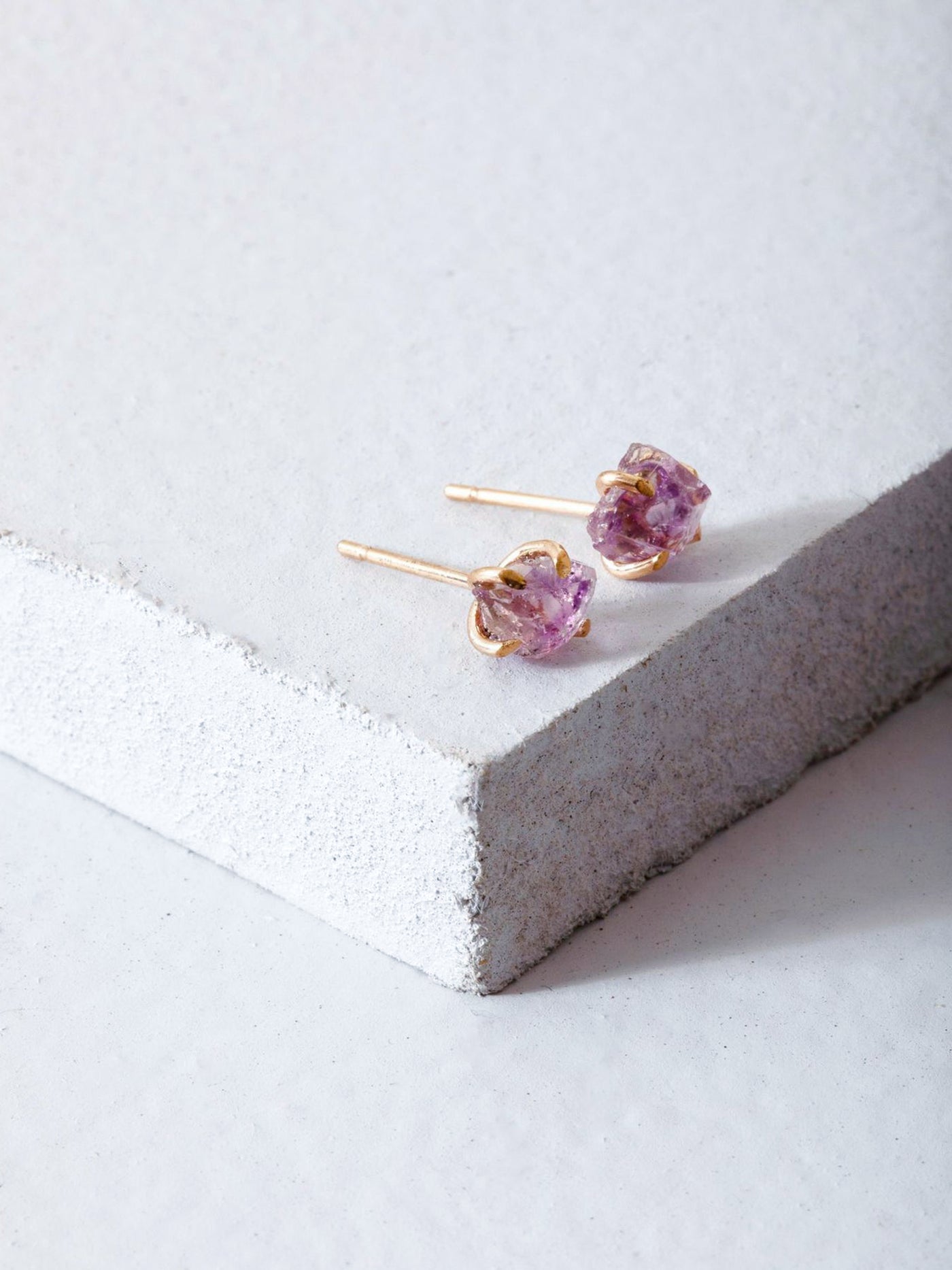 Raw Amethyst Gold Stud Earrings. These versatile raw amethyst stud make for an ideal statement piece and are set in high quality 14k yellow gold prongs.