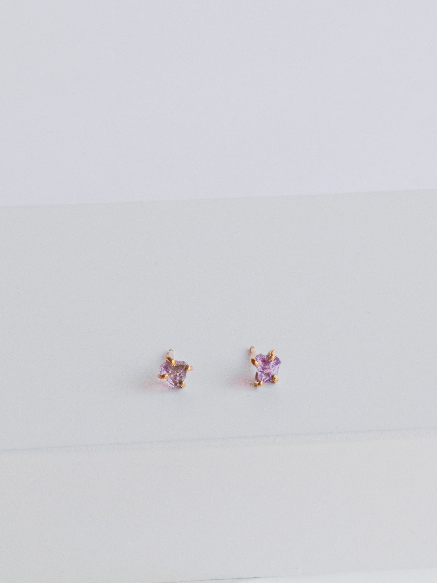 Raw Amethyst Gold Stud Earrings. These versatile raw amethyst stud make for an ideal statement piece and are set in high quality 14k yellow gold prongs.